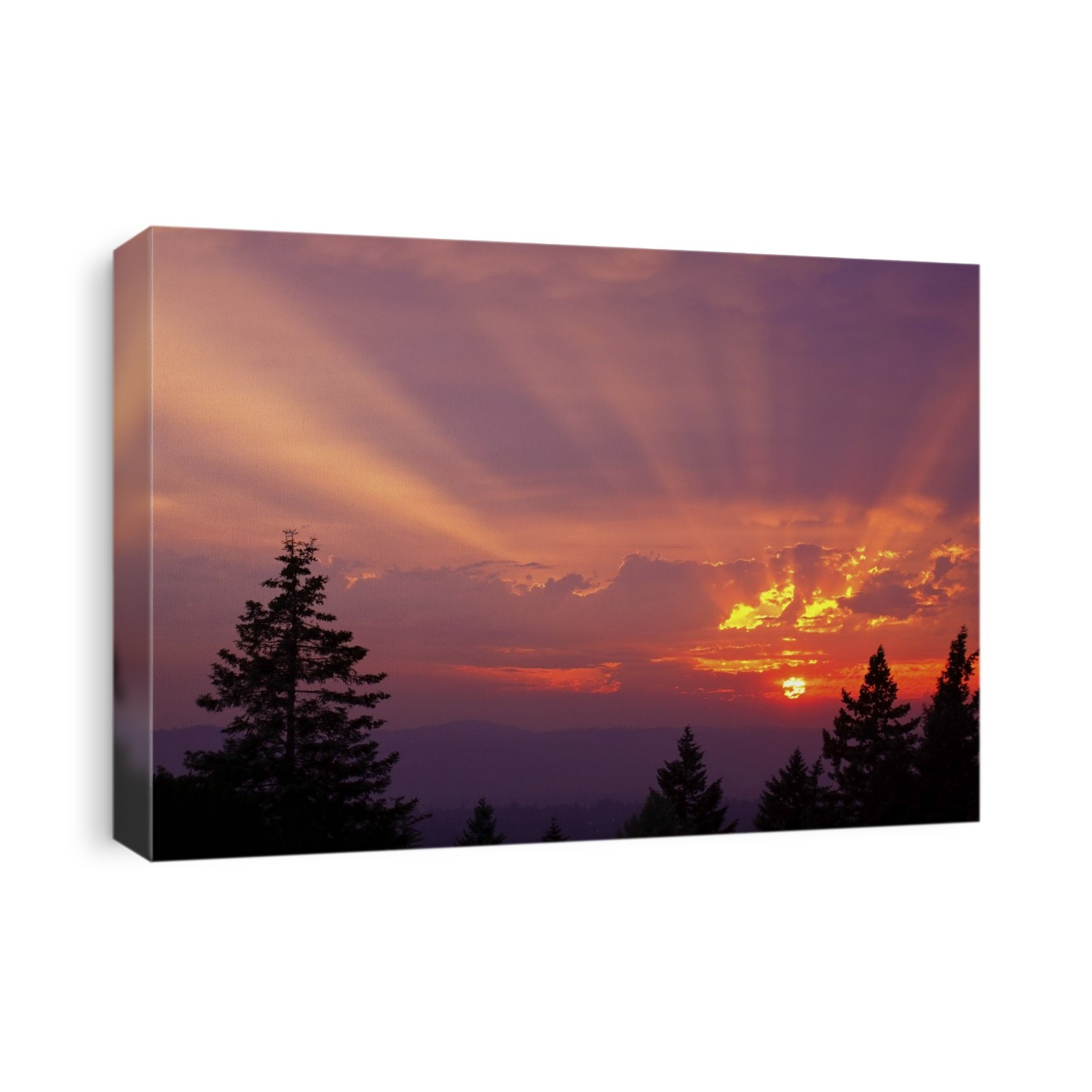 Dramatic sun glowing in a brilliant sunset sky over silhouetted mountains and treetops