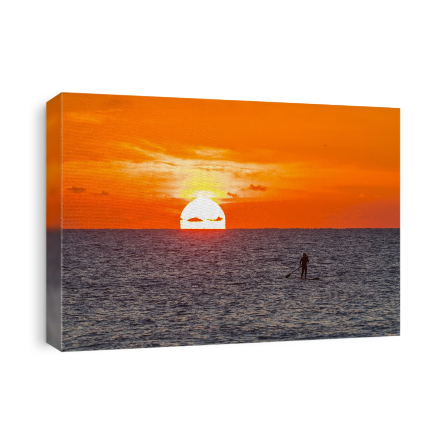 Silhouette of woman paddleboarding on the Atlantic Ocean off the coast of Indialantic with vibrant orange sky and glowing sun rising on the horizon; Florida, United States of America