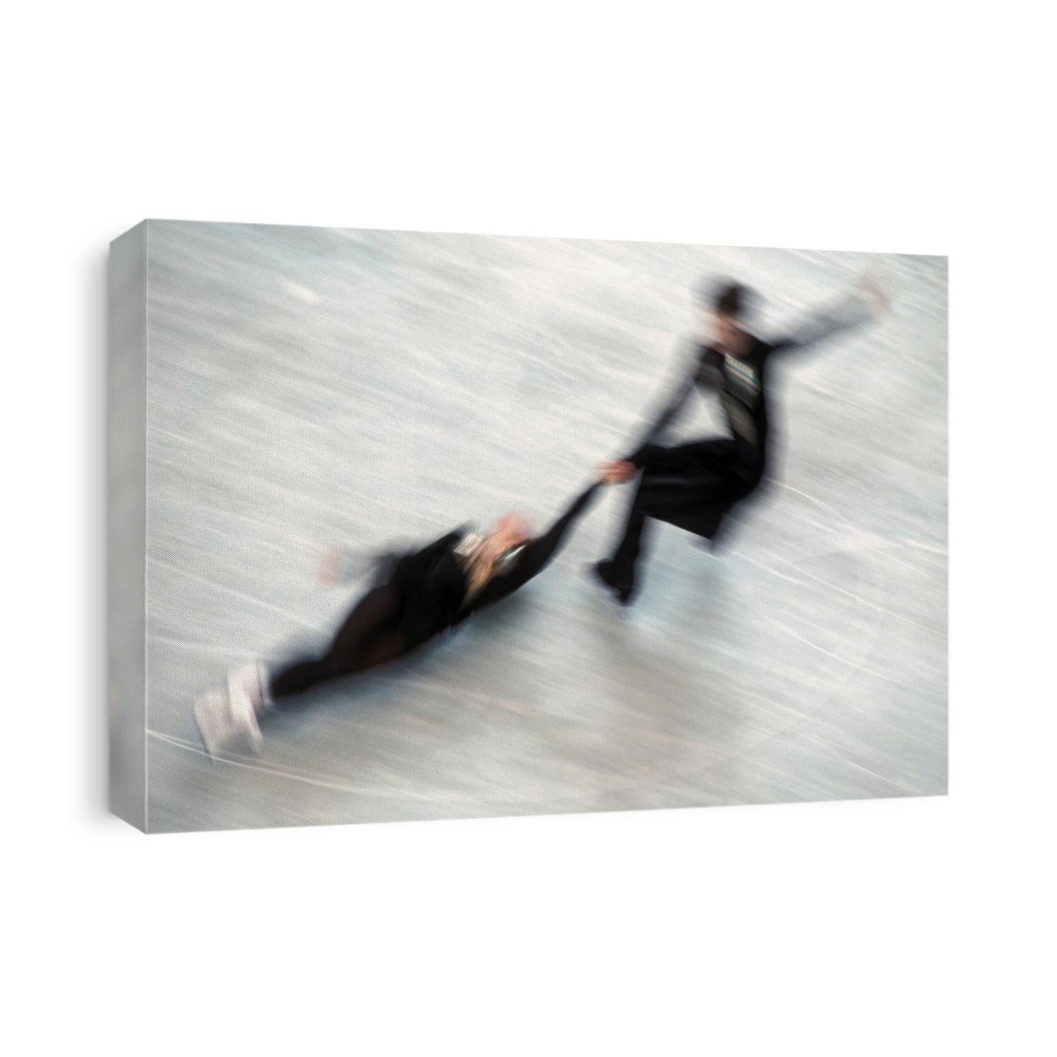 Blured action of pairs figure skaters doing a death spiral.
