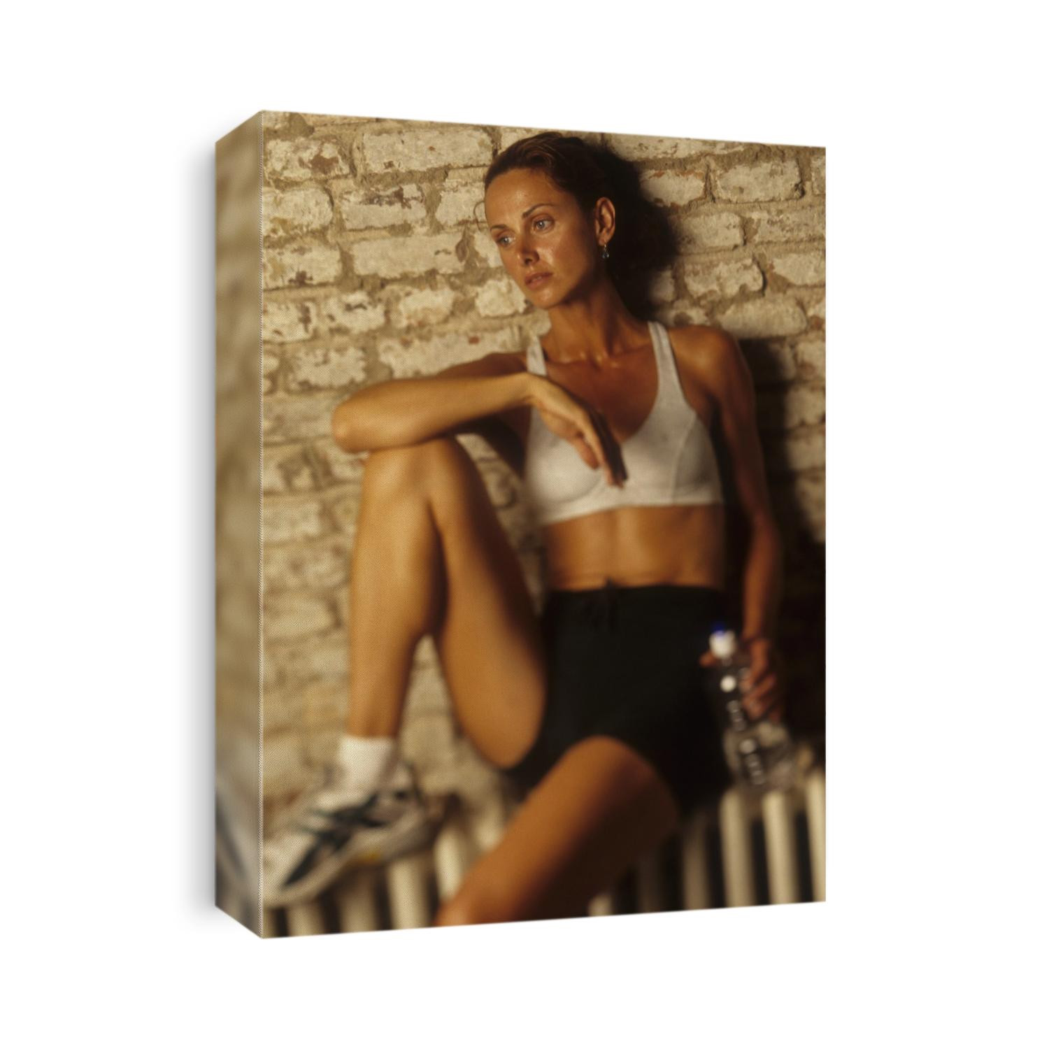 Woman resting and drinking after work out at health club.