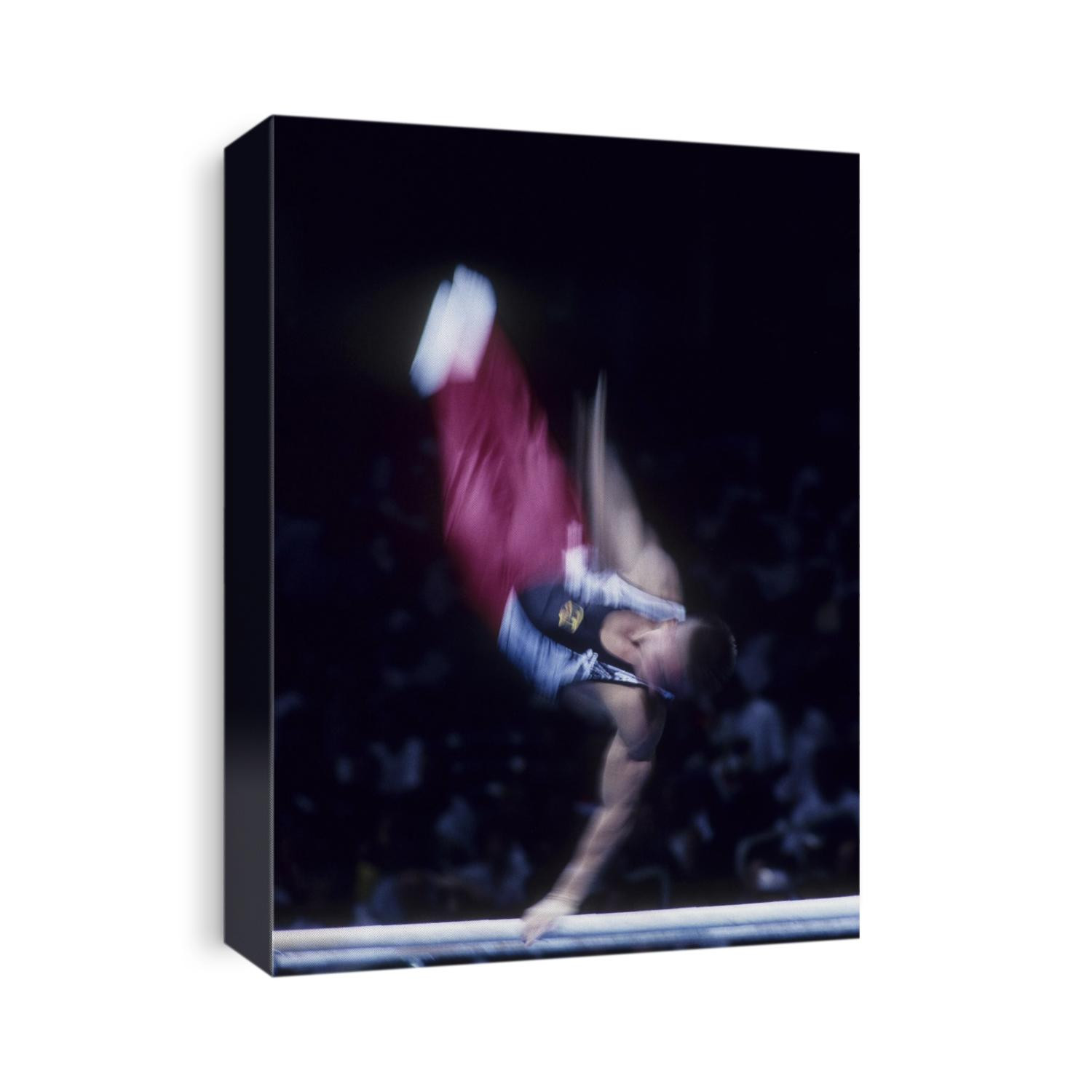 Blurred action of male gymnast preforming on the parallel bars.
