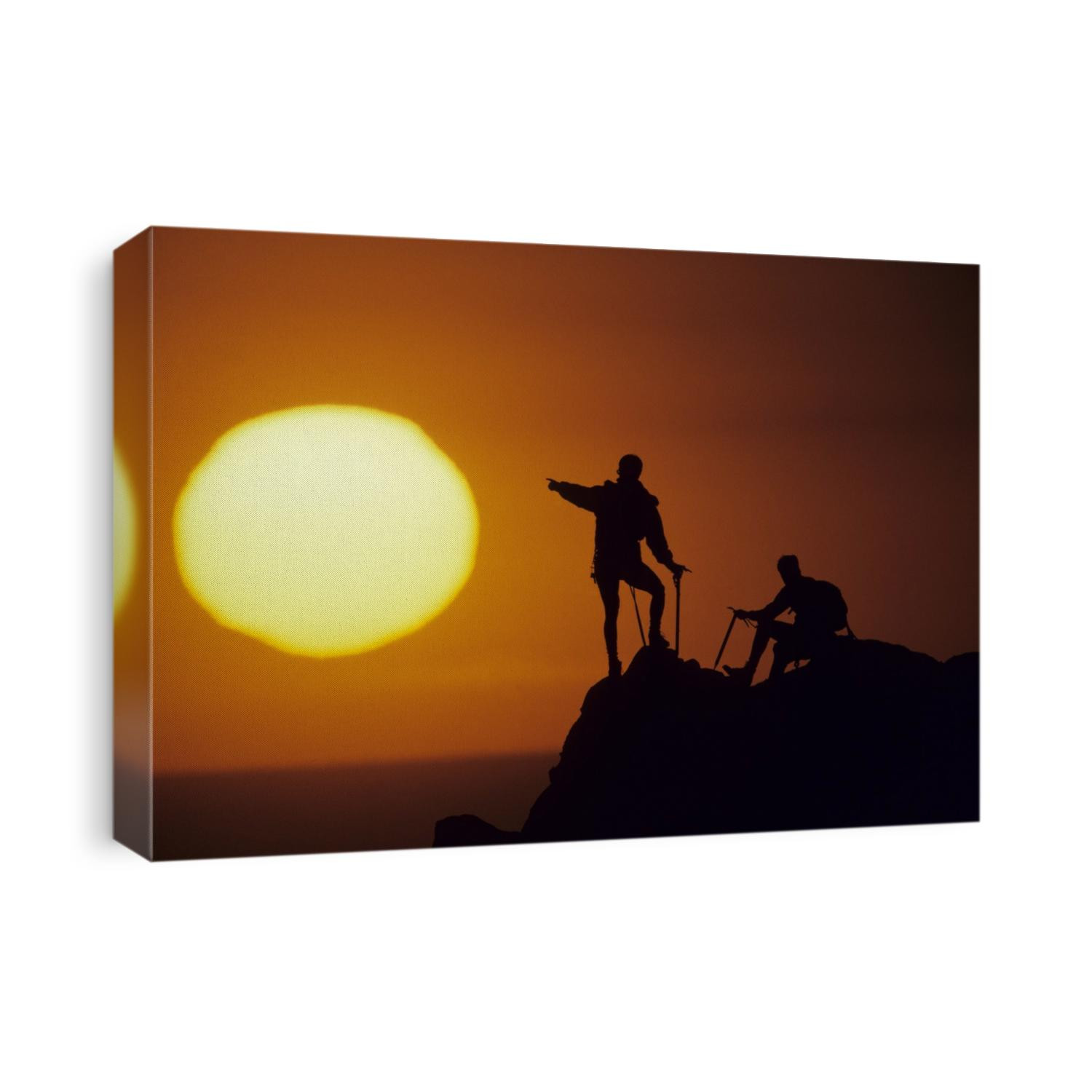 Two mountain climbers at sunset.