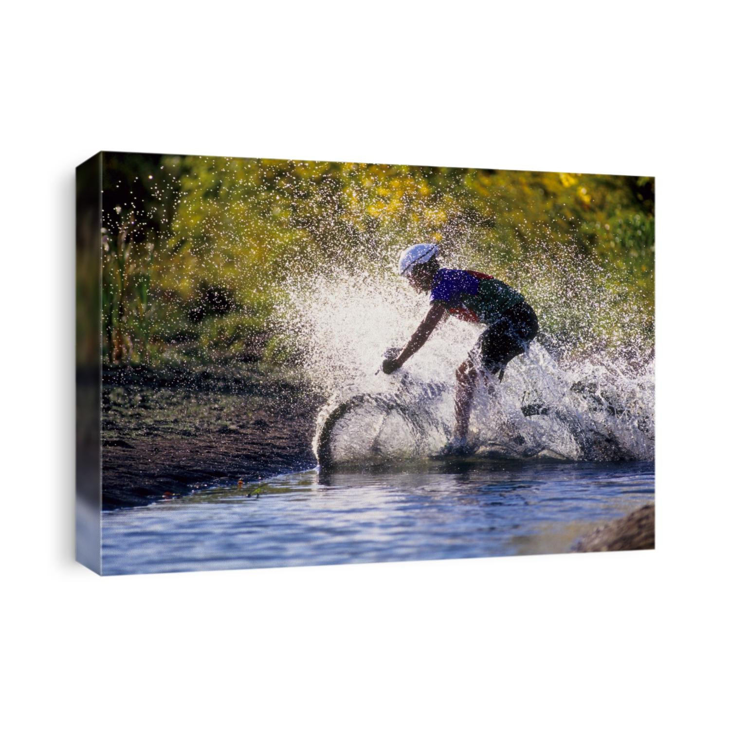 Moutain biker riding through a stream.