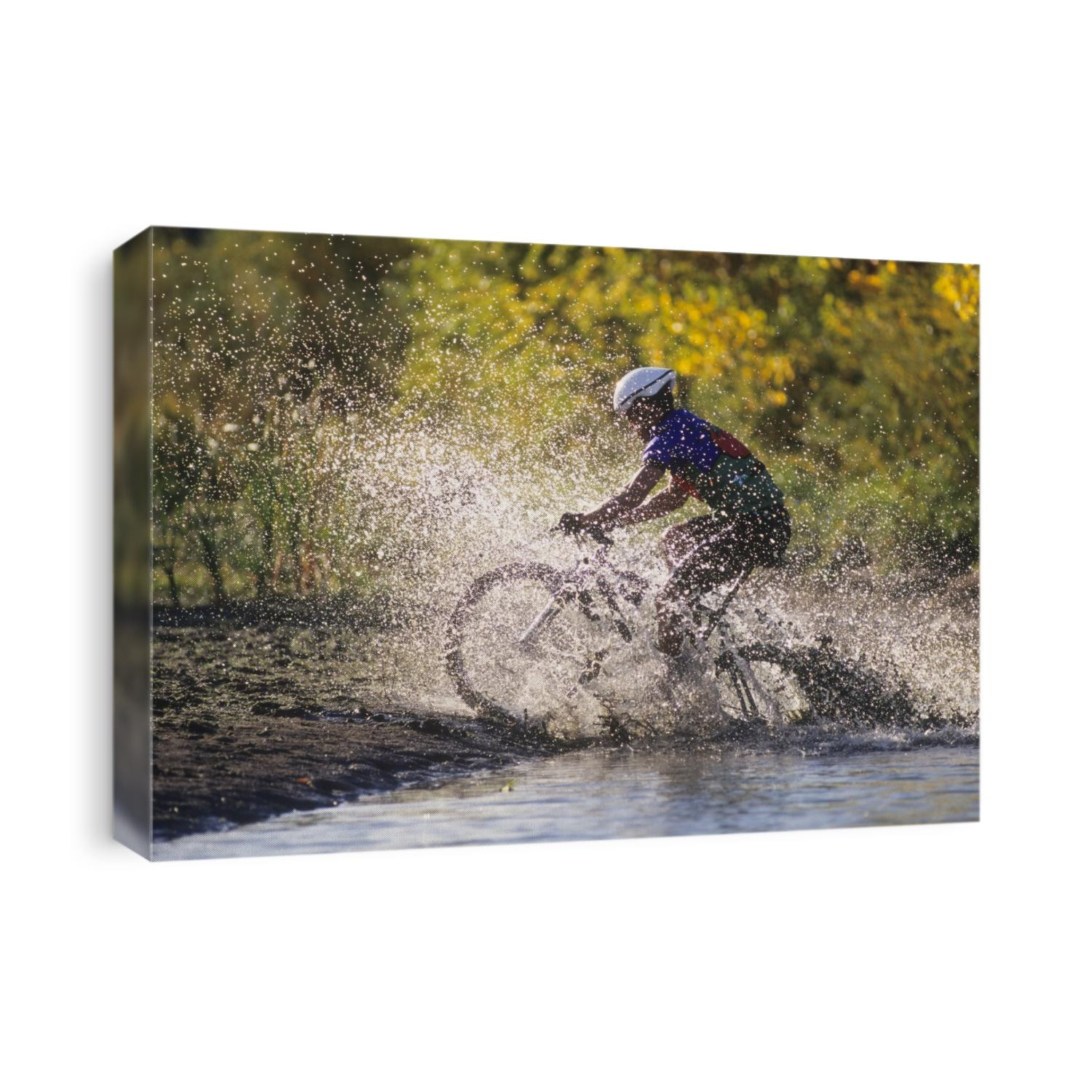 Moutain biker riding through a stream.