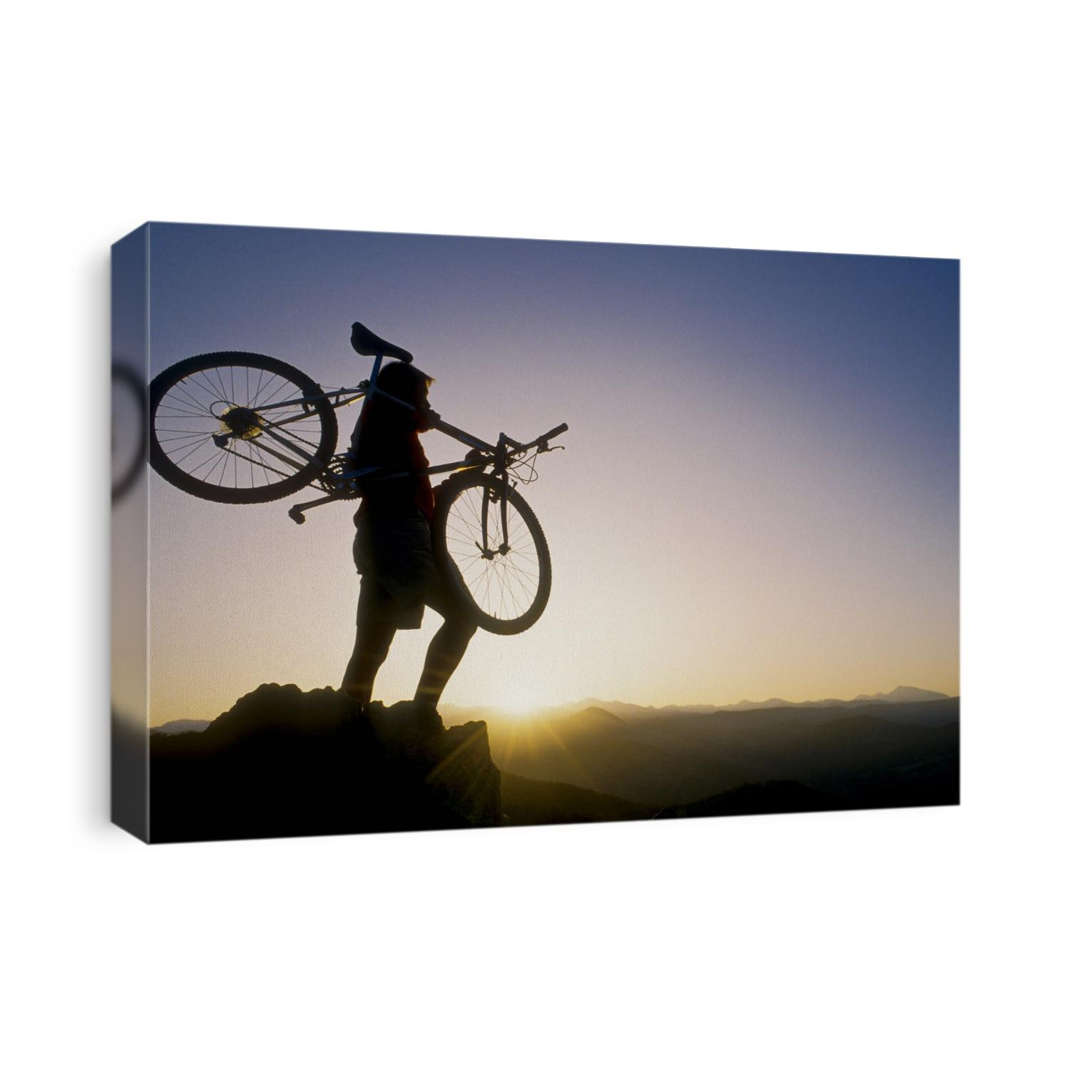 Silhouette of mountain biker at the summit during sunrise.