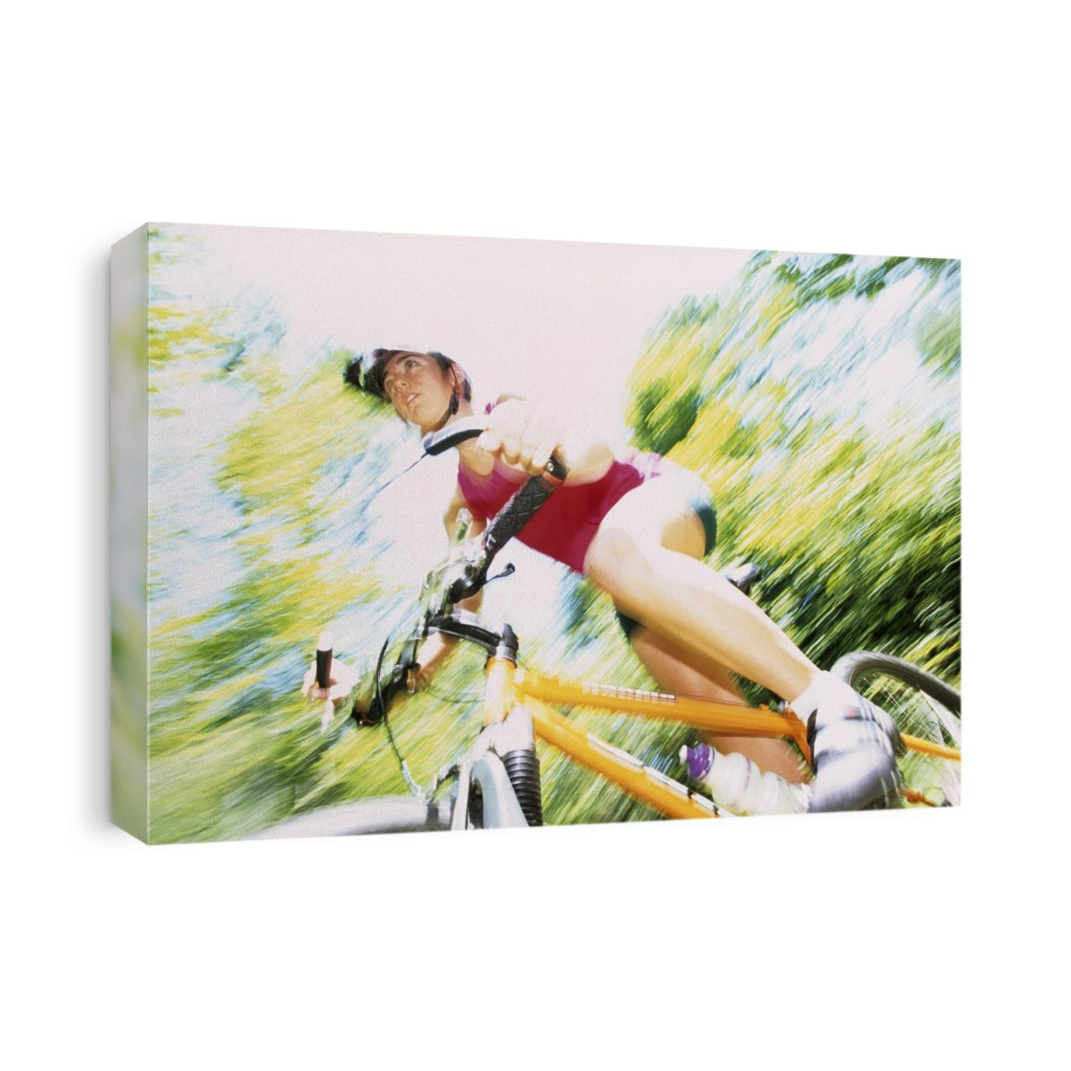 Action of female cyclist on mountain bike riding throught the woods.
