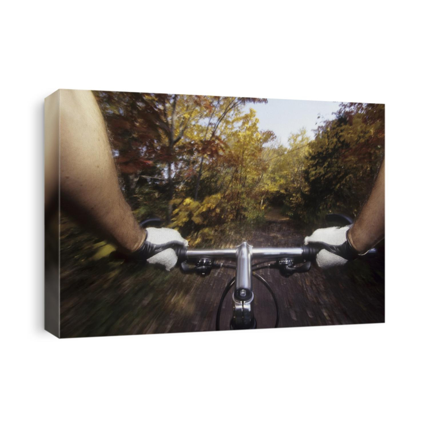 Detail of man's hand holding onto the handle bar of a mountain bike riding on the trails.