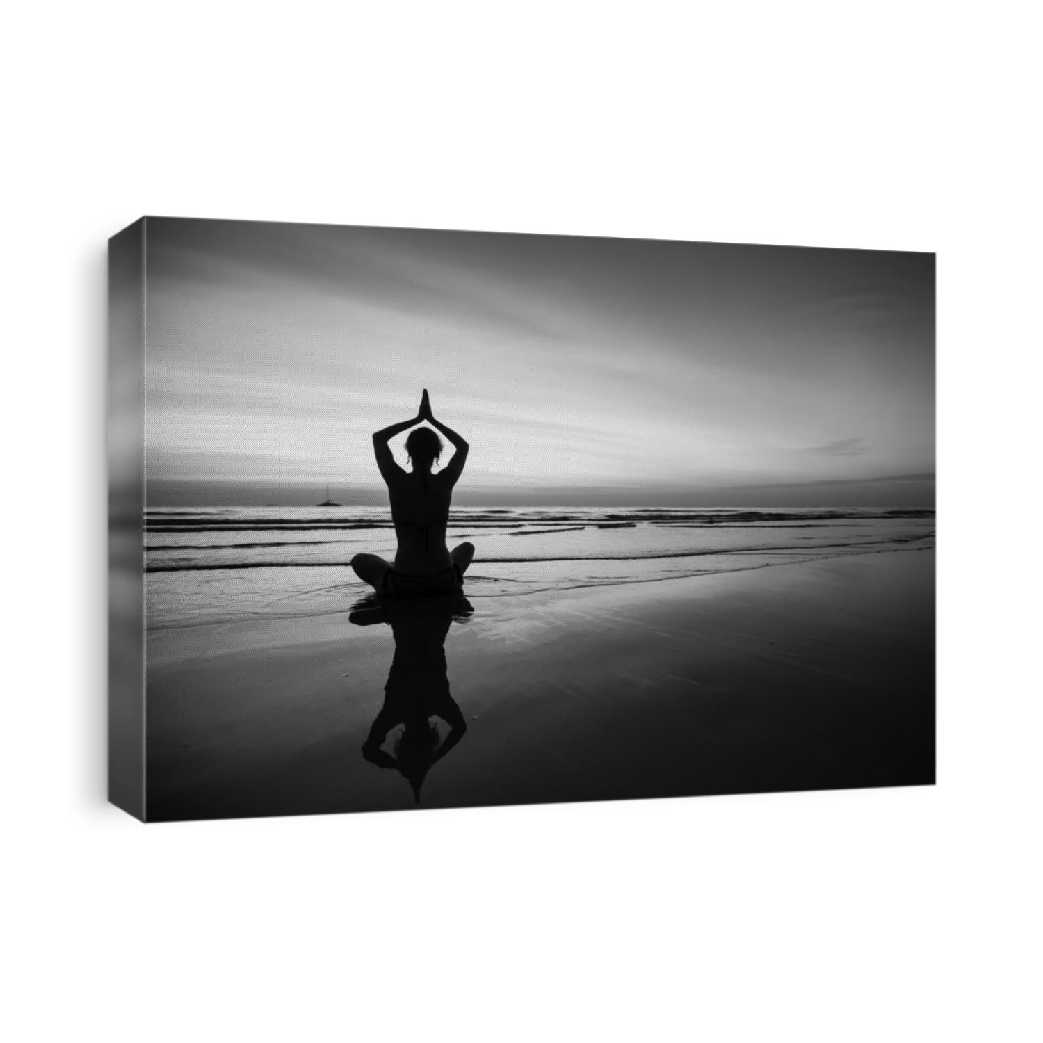 Woman doing meditation near the ocean beach. Black and white silhouette.