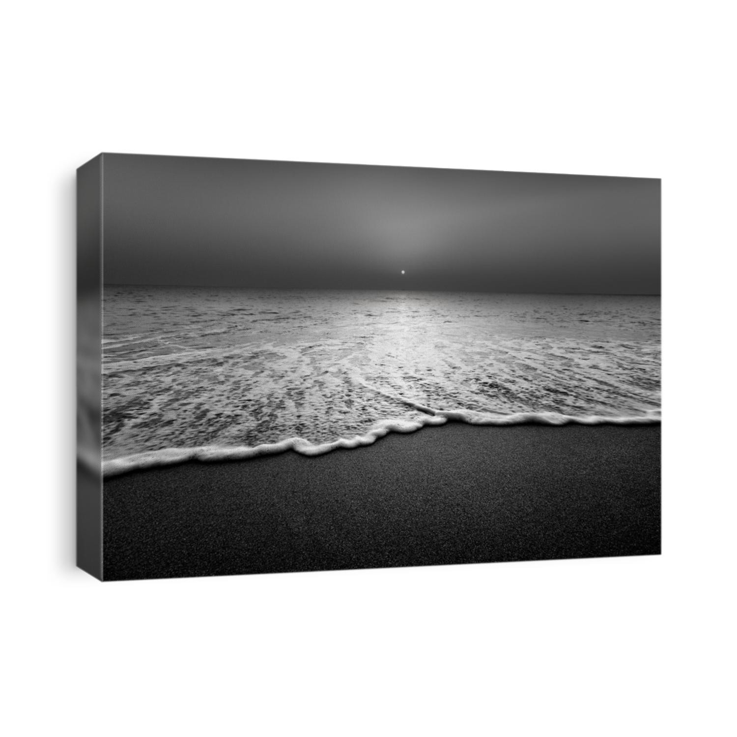 Wave and sandy beach in black and white. Calm view during sunset at seaside.
