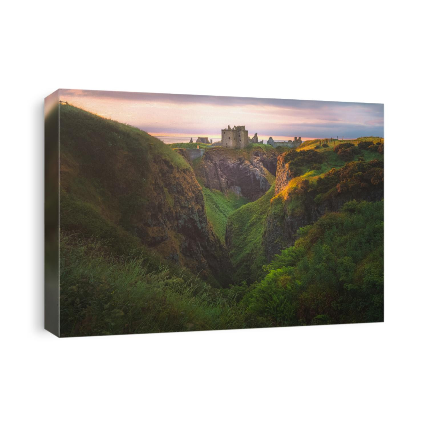 Golden sunrise or sunset light on the coastal landscape ruins of Donnottar Castle on the Aberdeenshire coast of Scotland.