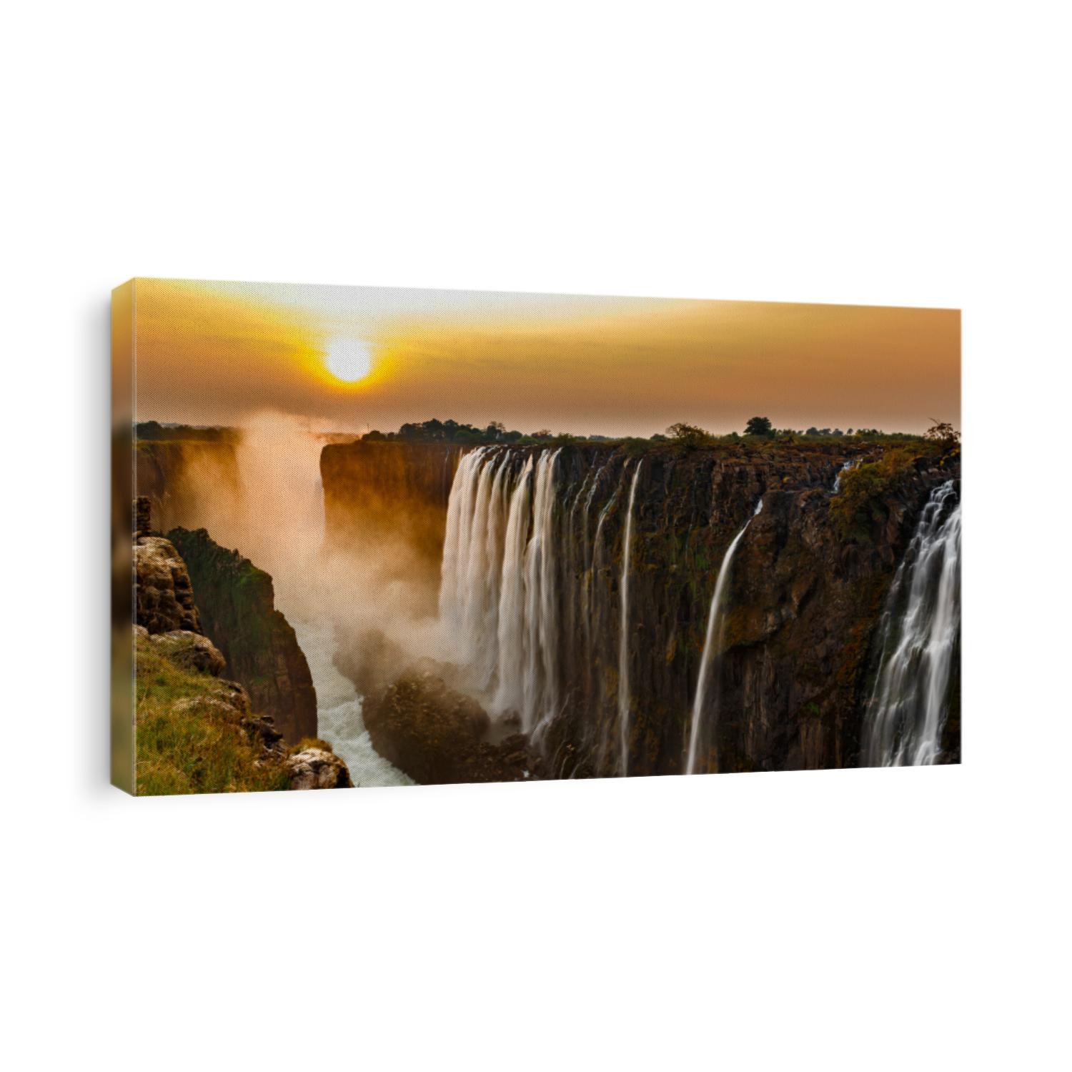 Wide panorama of victoria falls at sunset with orange sun in the sky and tourist in viewpoint